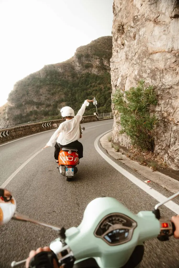 person on orange scooter driving on coastal road in Amalfi