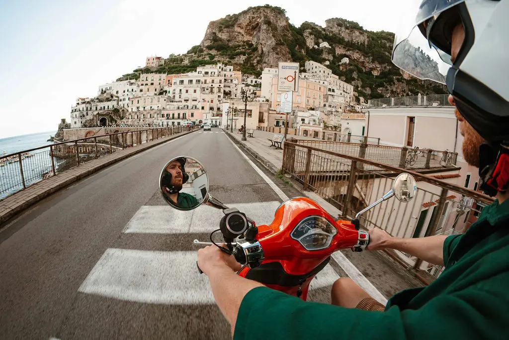 man on red vespa scooter driving through Amalfi Coast town
