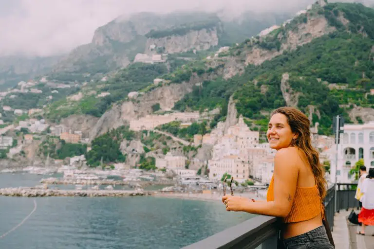 woman smiling at Amalfi Coast village and mountains