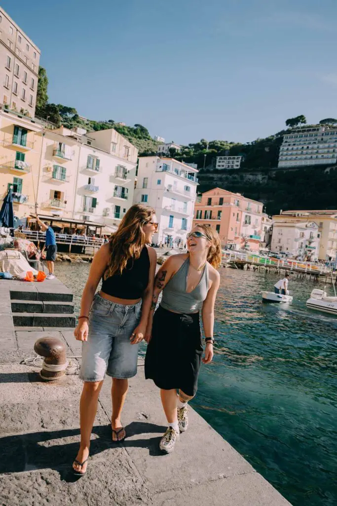 two women laughing on a pier in a coastal Italian village