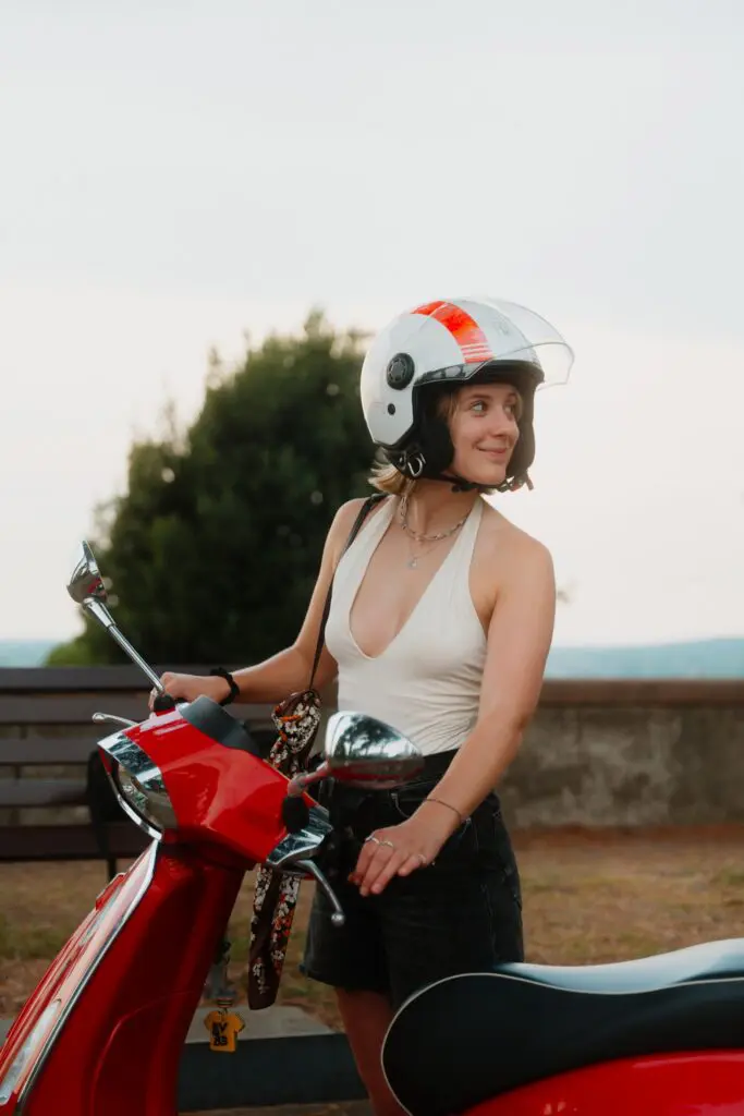 jonge vrouw met helm op een rode Vespa-scooter
