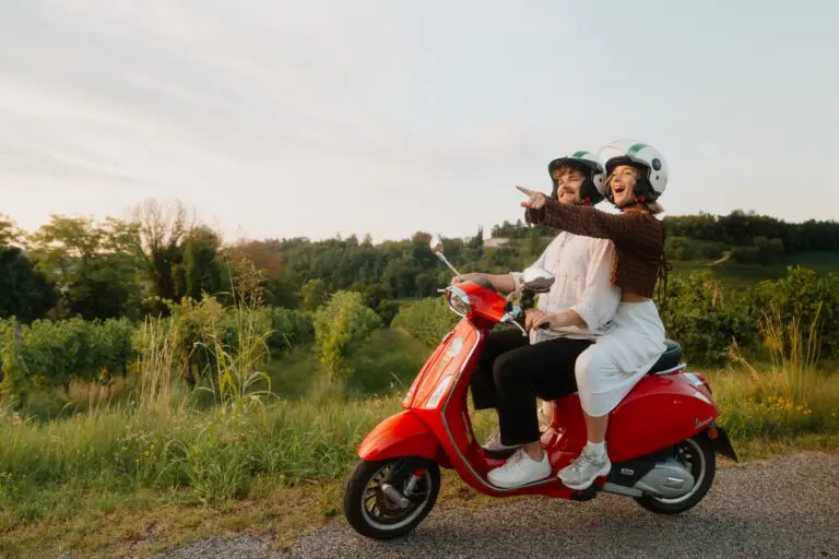 couple riding red vespa through veneto vineyards at sunset