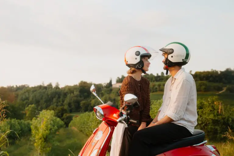 stel dat naar elkaar kijkt op een rode Vespa in een wijngaard in Veneto