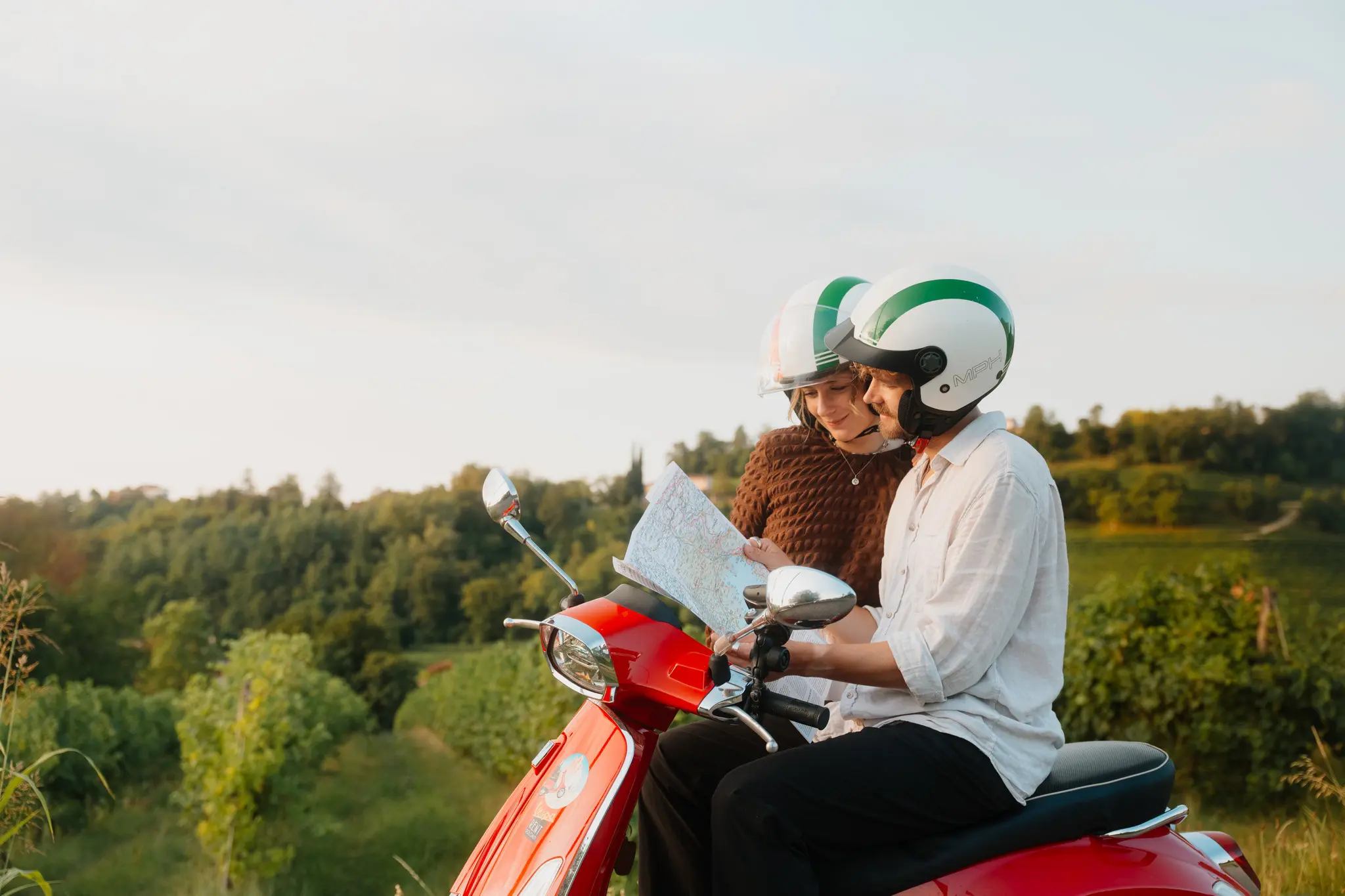 stel op een rode Vespa-scooter kijkt naar een kaart in Veneto