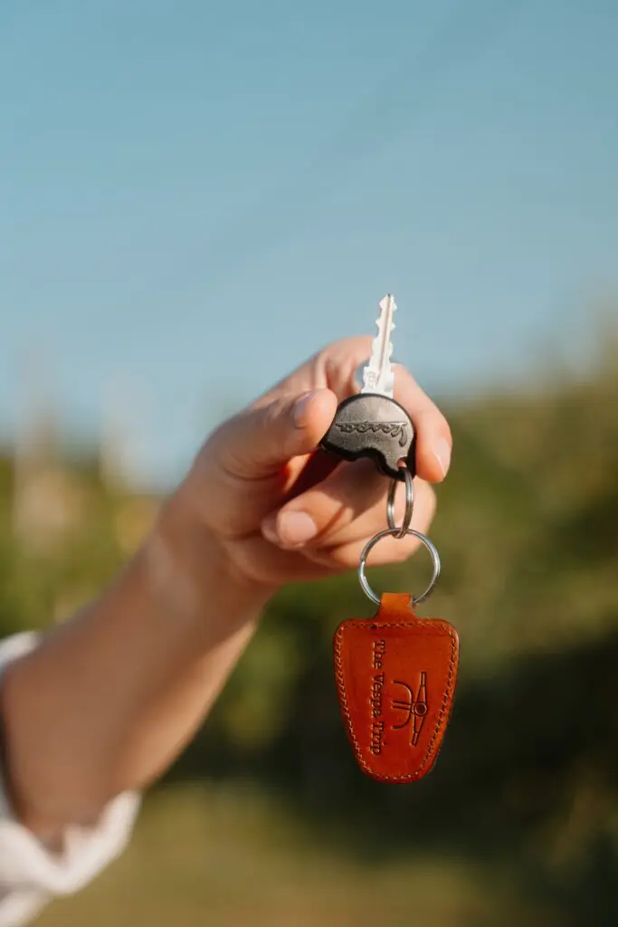 hand die een Vespasleutel met leren sleutelhanger vasthoudt