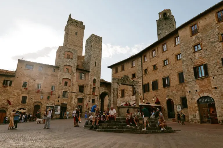 people relaxing in a historic town square in Tuscany, Italy