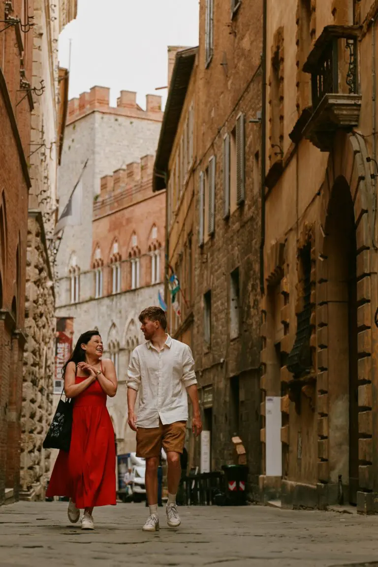 couple walking and laughing in a narrow Siena street