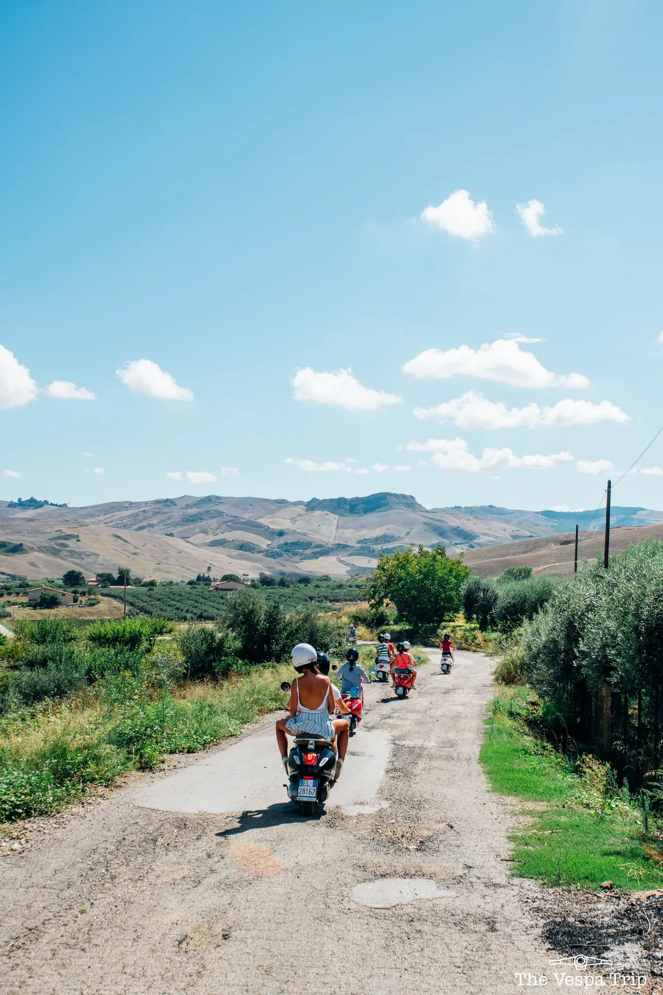 groep mensen die op Vespa's over een landelijke weg op Sicilië rijden
