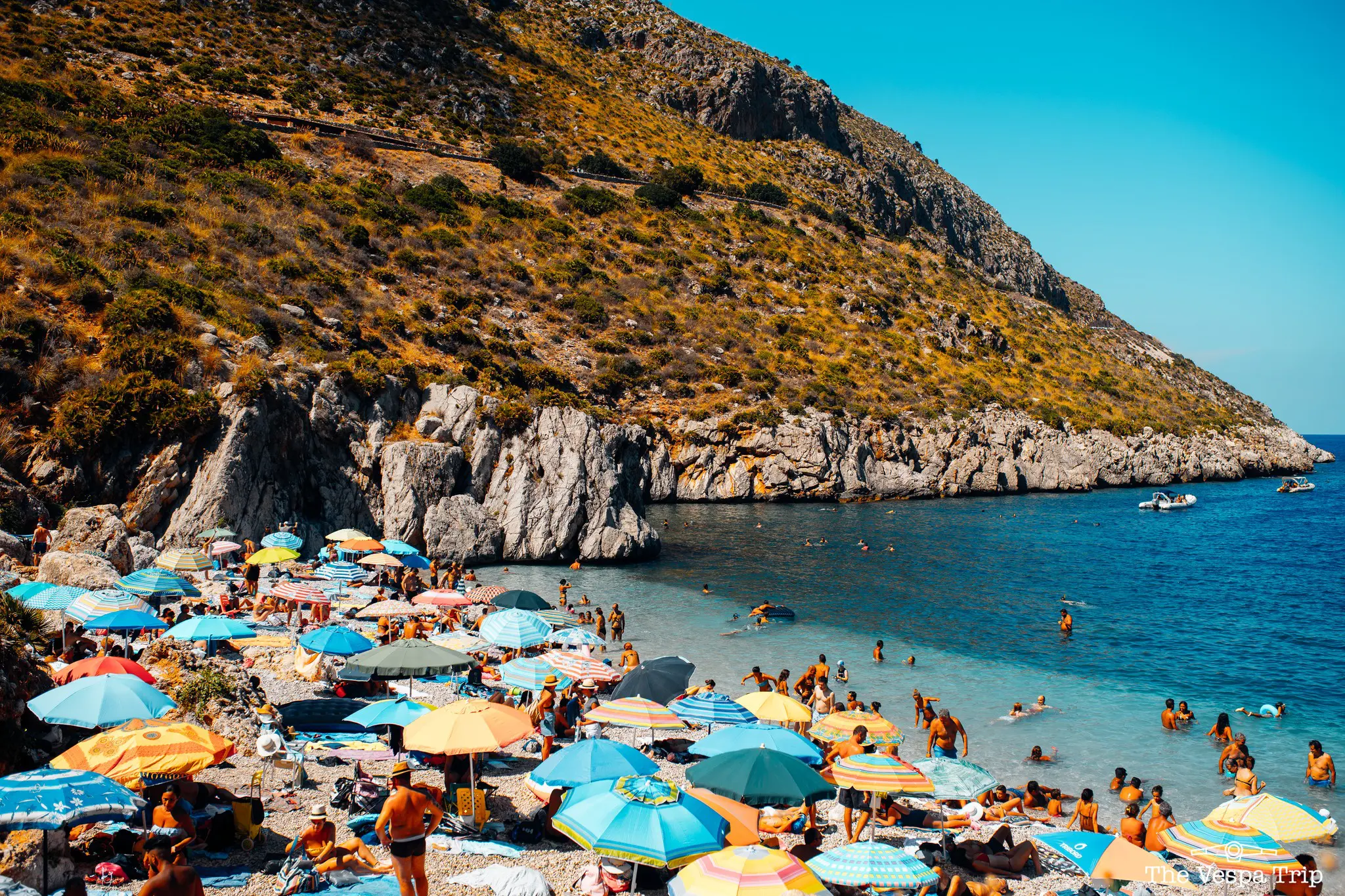 druk strand met kleurrijke parasols en zwemmende mensen op Sicilië