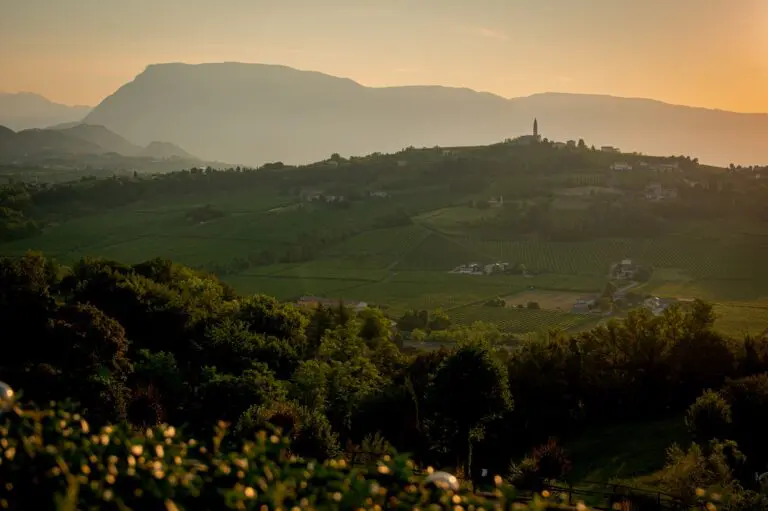 wijngaarden en dorp met klokkentoren bij zonsondergang in Veneto