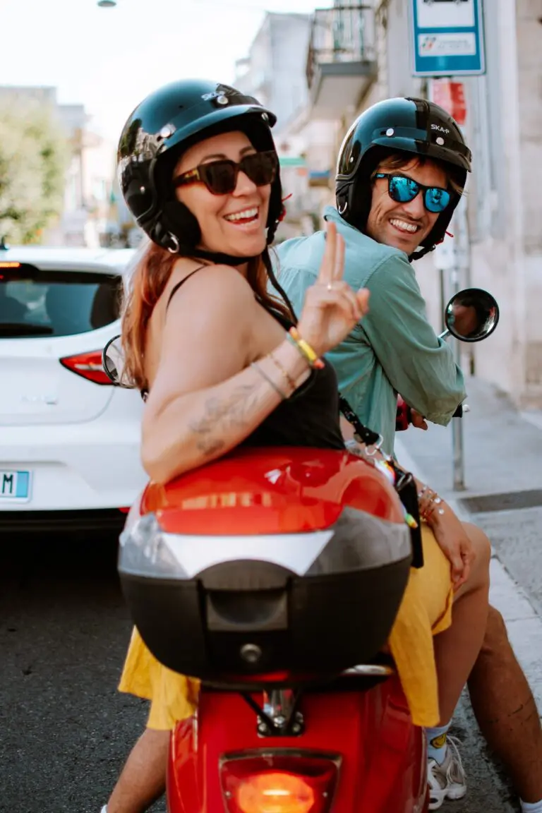 couple on a red scooter smiling in Puglia, Italy