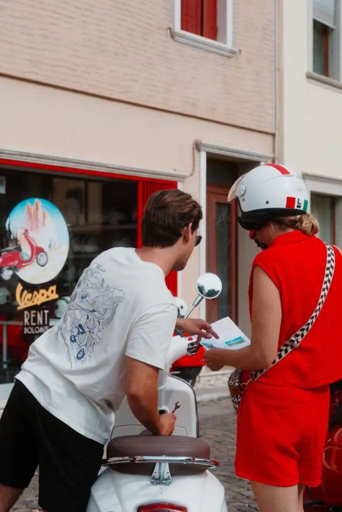 couple looking at map next to a white Vespa scooter