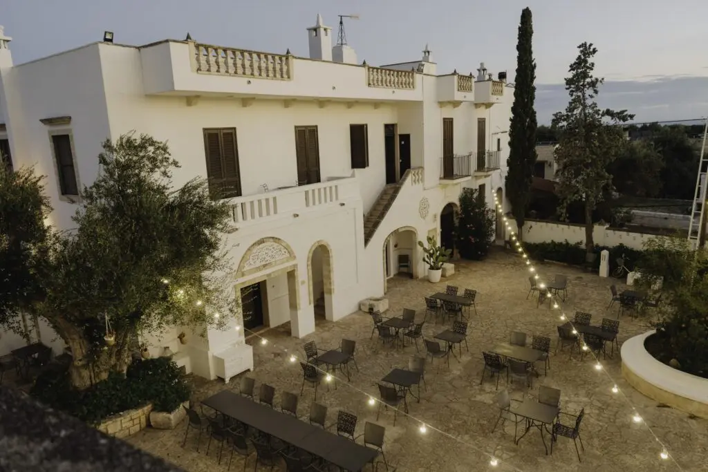 courtyard of a white building with string lights and tables