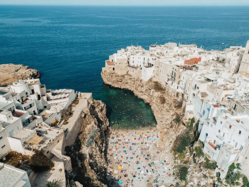 drone shot of Polignano a Mare beach and white cliffside town