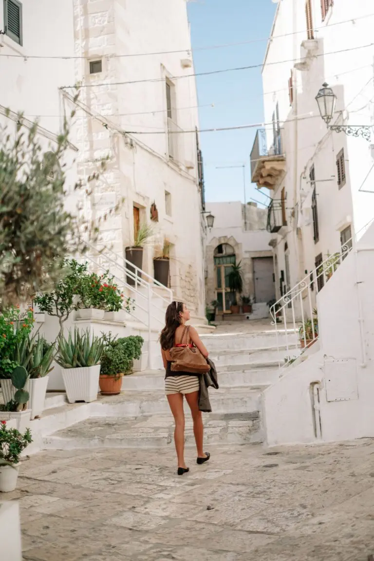 woman walking up steps in a white village in Puglia