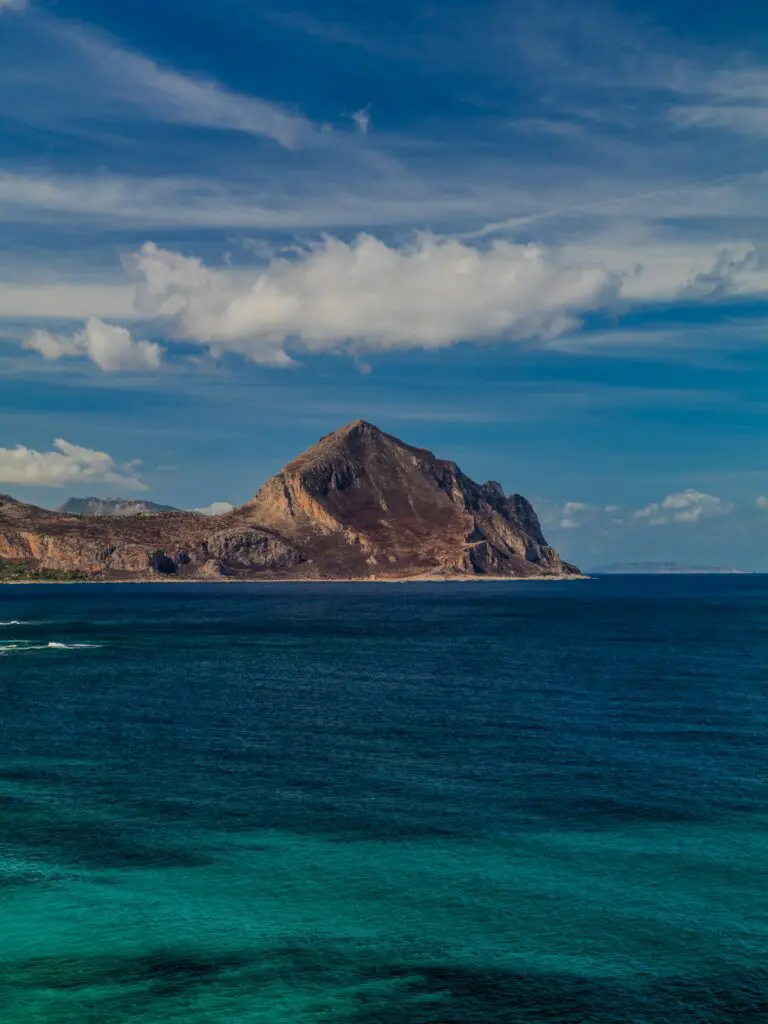 Mountainous coastline meets turquoise ocean under blue sky