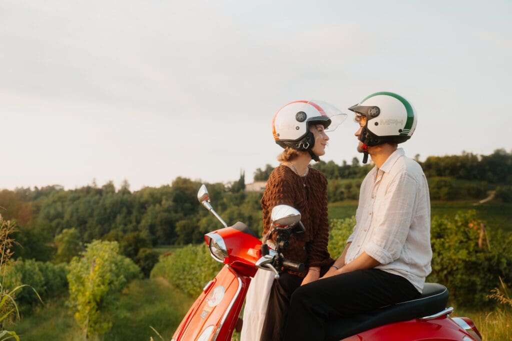 couple on red vespa looking at each other in Veneto vineyard