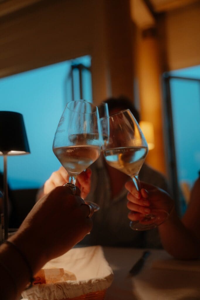 two people toasting with white wine glasses at night