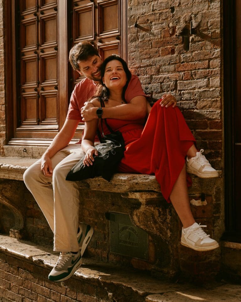 happy couple sitting on stone steps in Tuscany