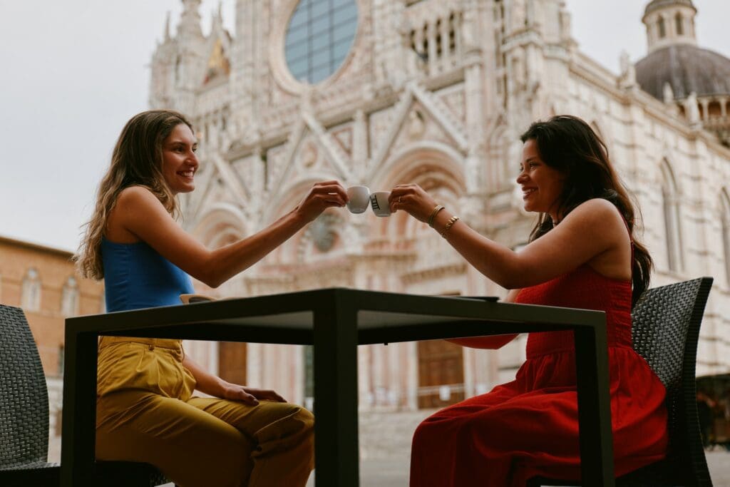 twee vrouwen die met espresso proosten voor de kathedraal van Siena