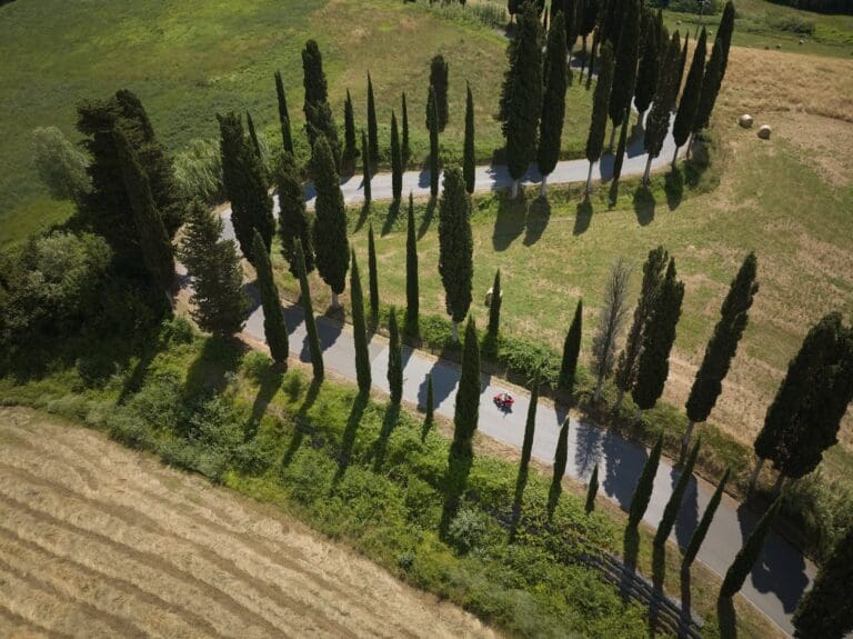 drone-opname van een rode scooter op een kronkelende weg in Toscane