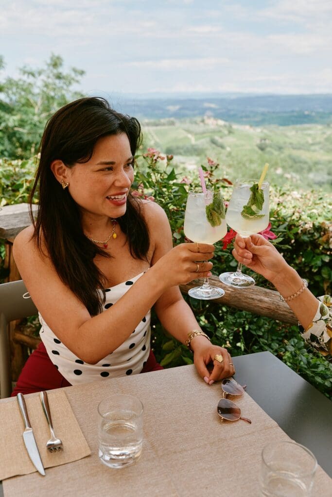 twee vrouwen die op een terras met uitzicht over Toscane het glas heffen