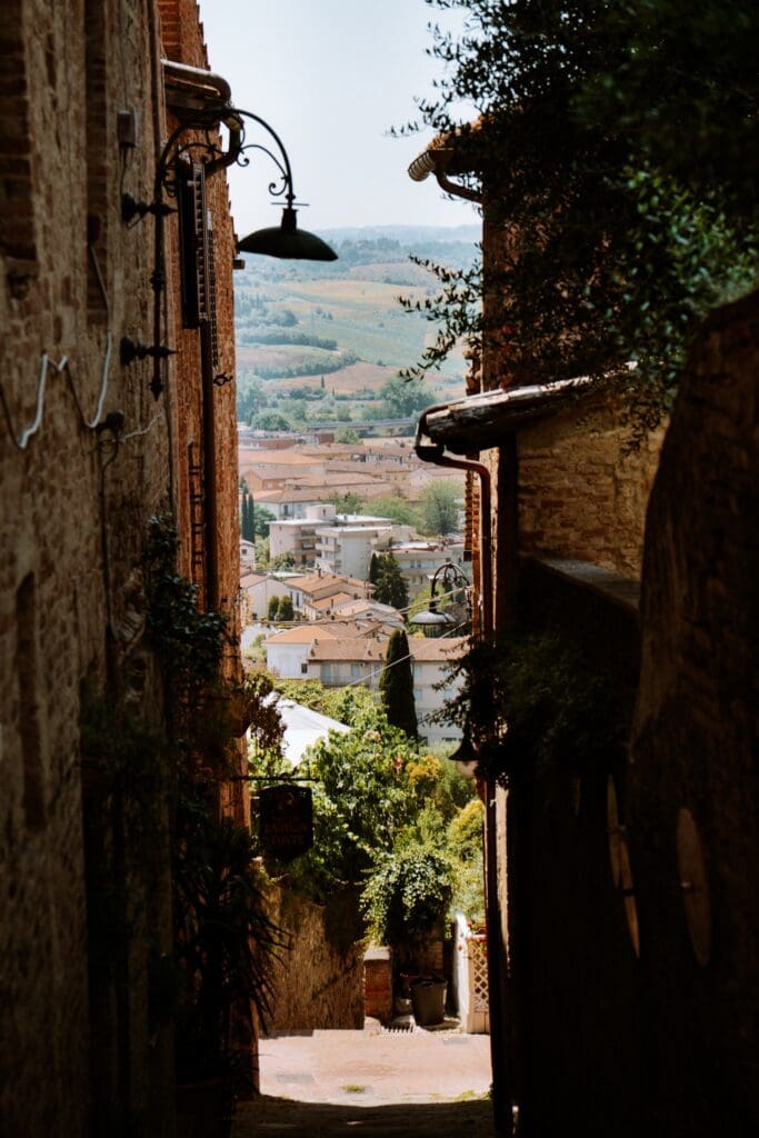 narrow alleyway in an Italian village overlooking rolling hills