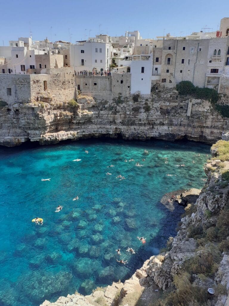 Polignano a Mare, stad op de kliffen met mensen die in turquoise water zwemmen