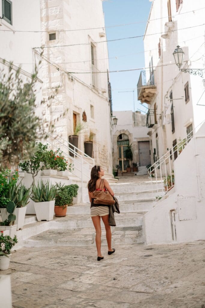 vrouw die een trap oploopt in een wit dorp in Puglia